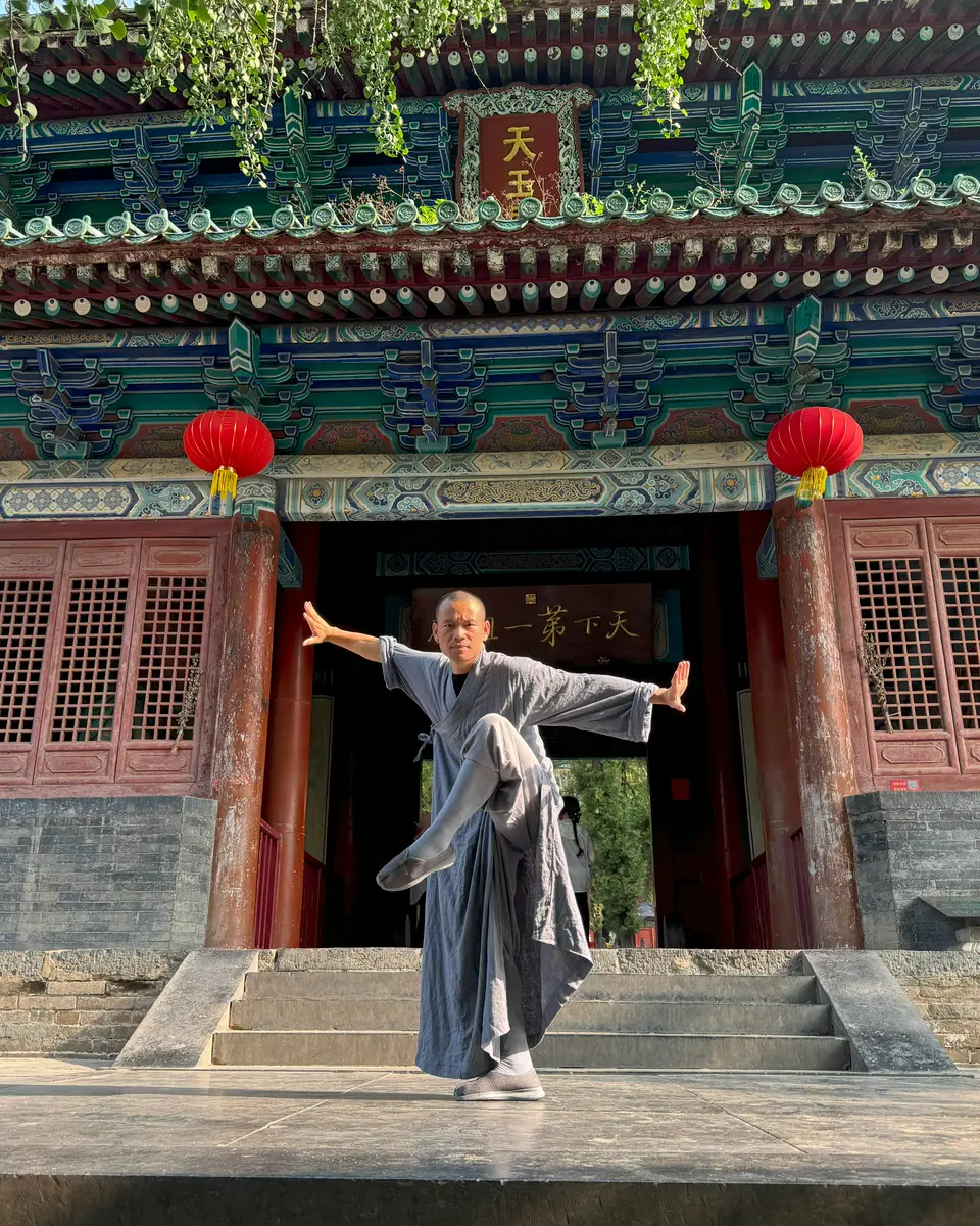 Grandmaster Shi Yan Bing in a Kung Fu stance in front of a hall of the Shaolin Temple